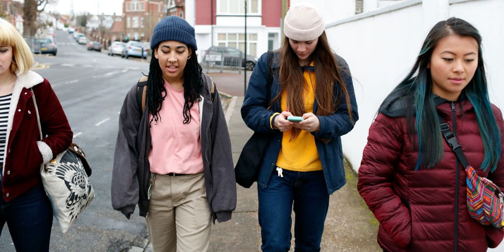 Four young female students walking down a road